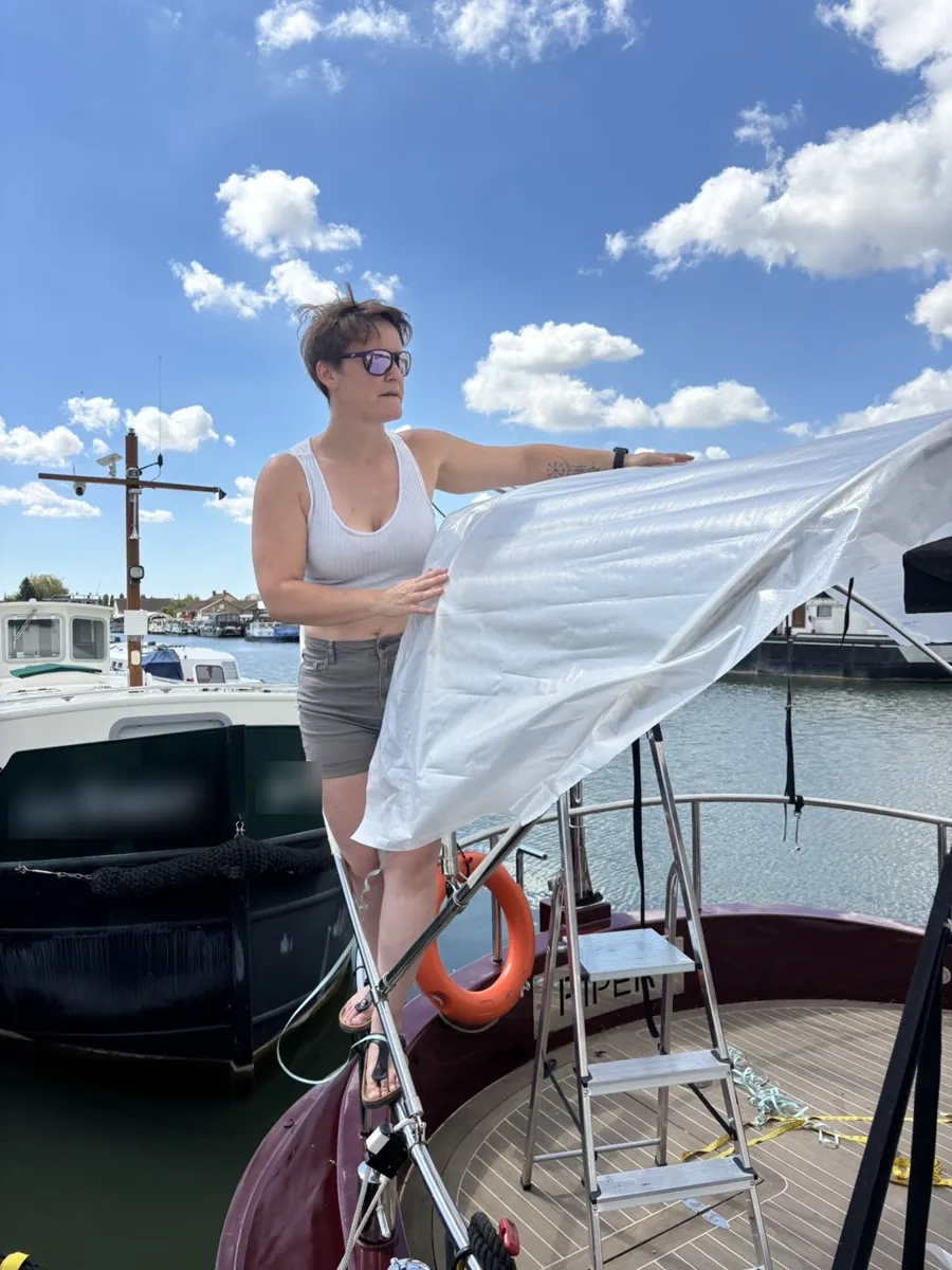 Laetitia ajustant une toile sur l’armature d’un bimini